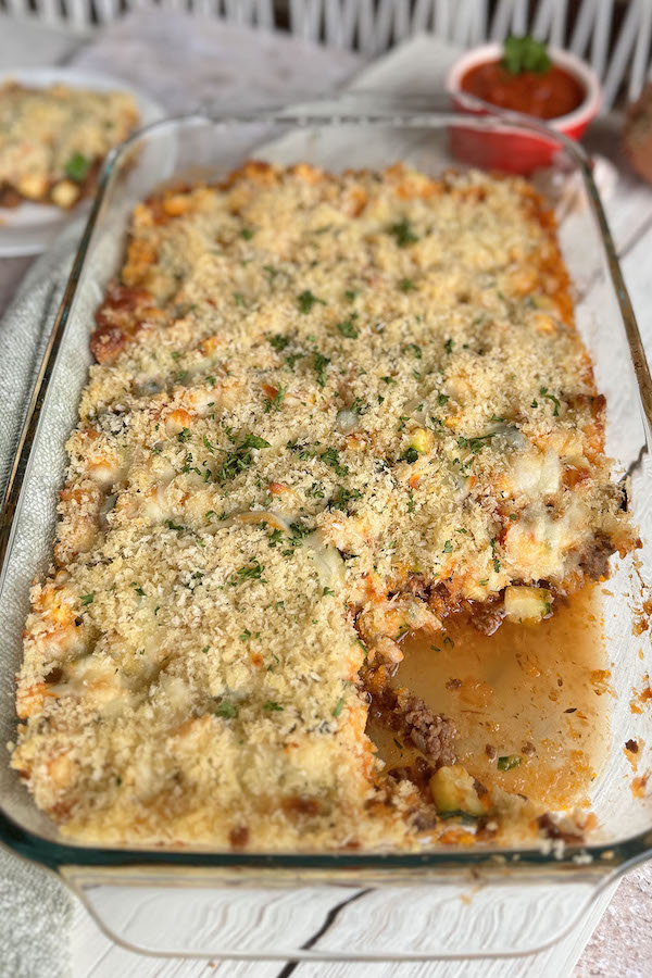 Zucchini and ground beef casserole in a baking dish topped with fresh chopped parsley.