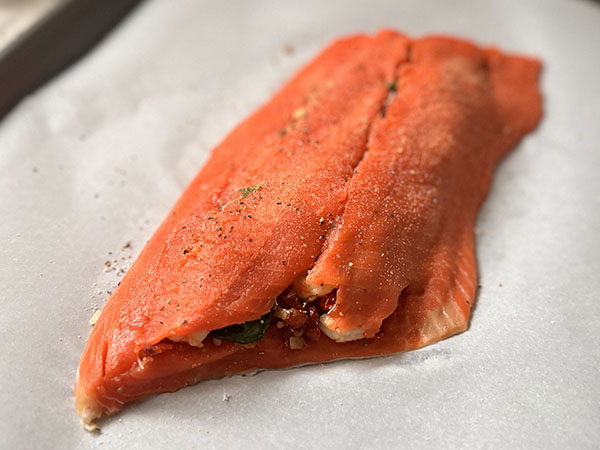 Closed stuffed salmon fillet seasoned on top.