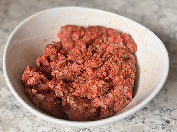 A bowl of raw taco seasoned ground beef.