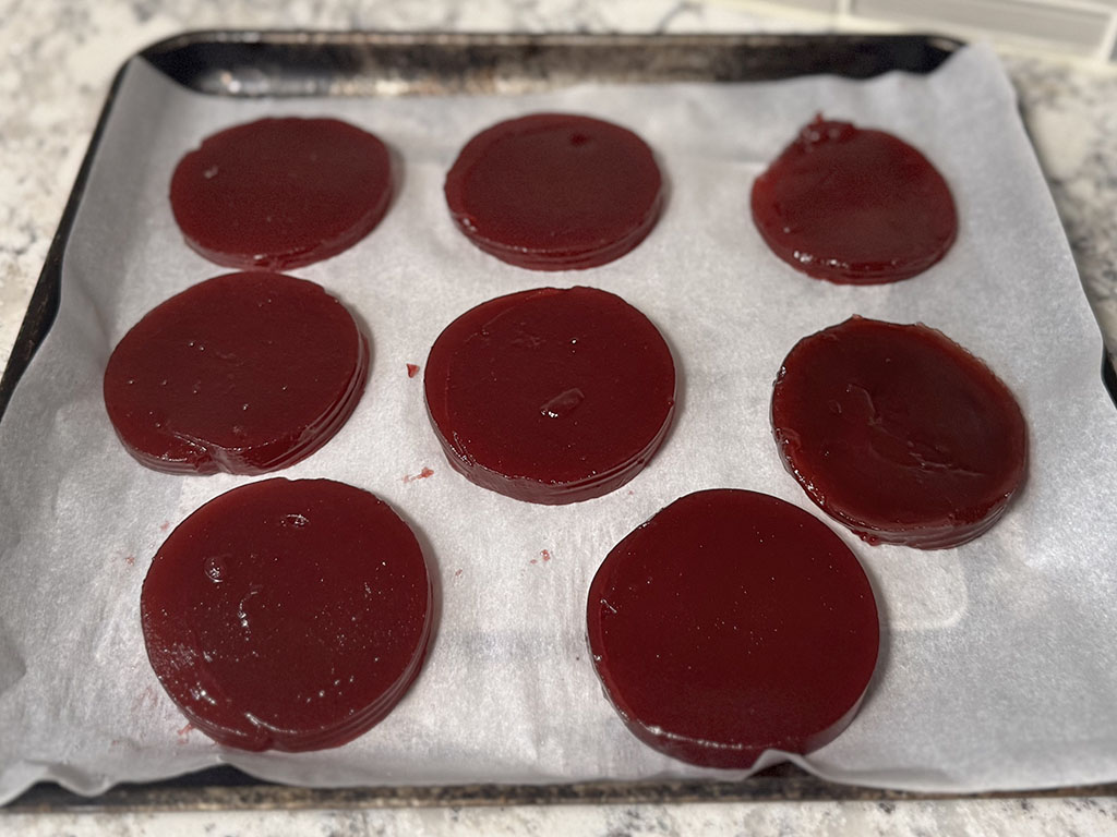 Jellied cranberry sauce slices on parchment paper ready for freezing.
