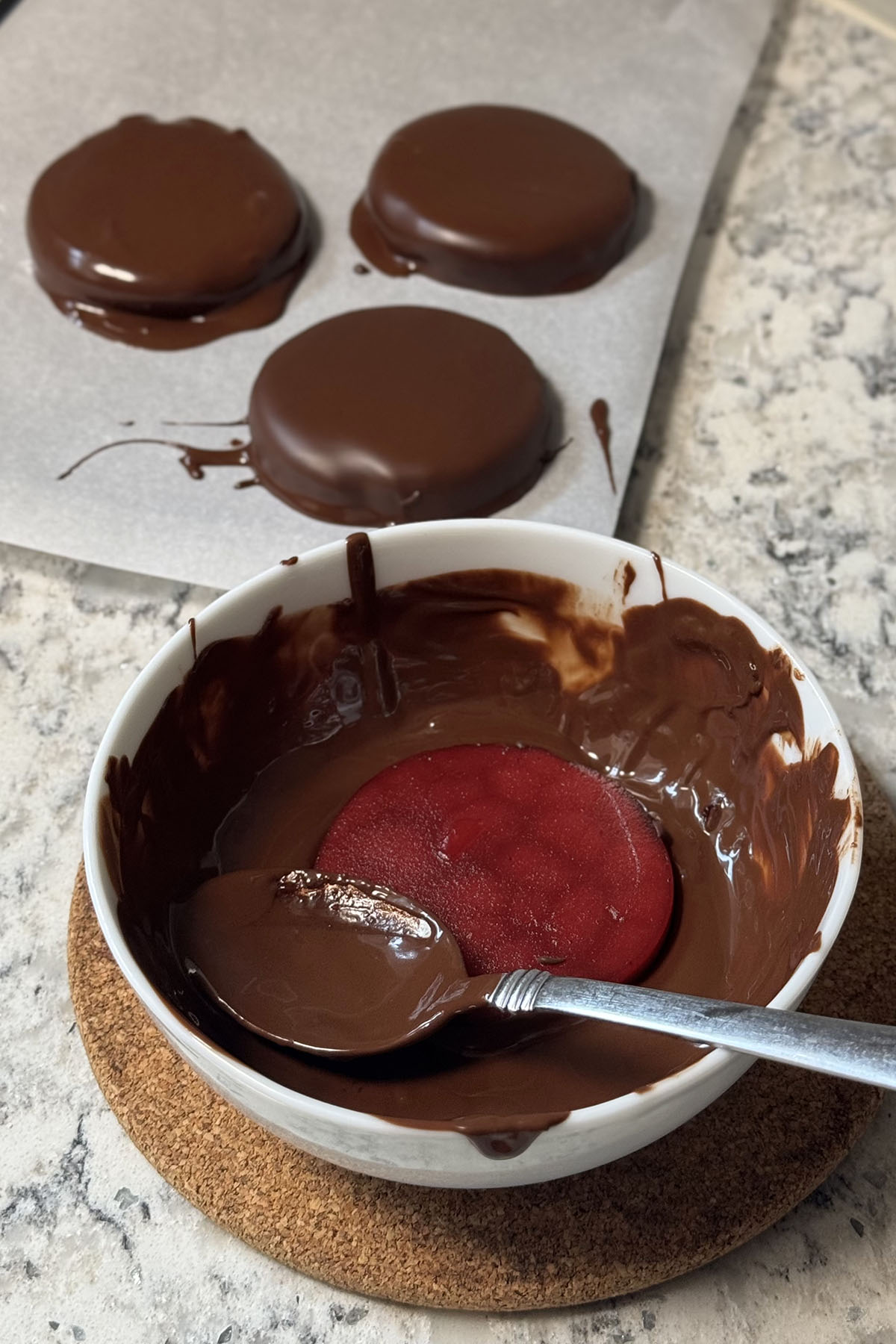 Jellied cranberry slice dipped in a bowl of chocolate.