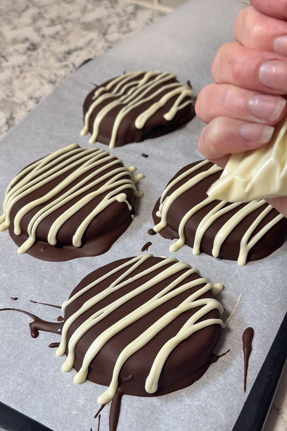 Cranberry-chocolate bites drizzled with white chocolate, and white chocolate in a ziplock bag with cut-off corner.