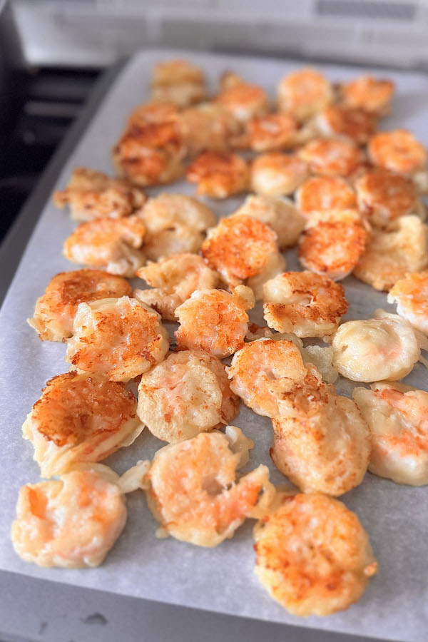 Fried shrimp resting on parchment paper.