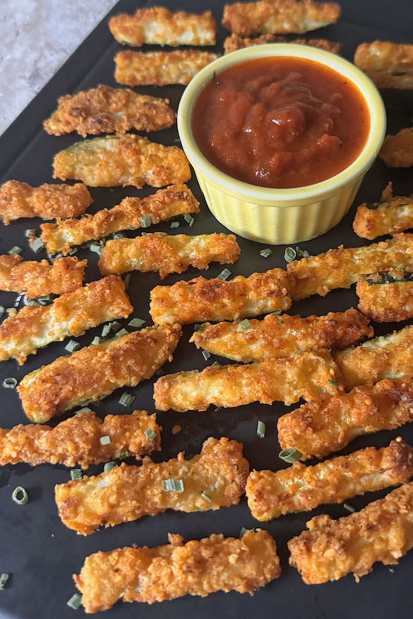 Golden crisp parmesan zucchini sticks served with marinara sauce for dipping.