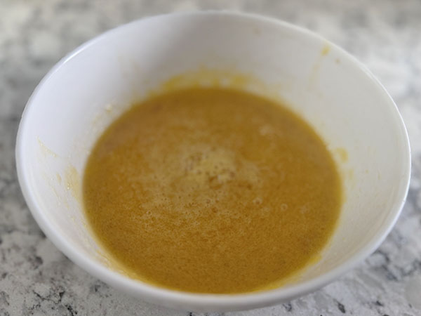 Wet ingredients for dairy-free pancakes: egg, vanilla, maple syrup and ghee.