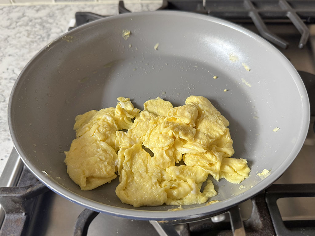 Fluffy cooked scrambled eggs in a skillet.