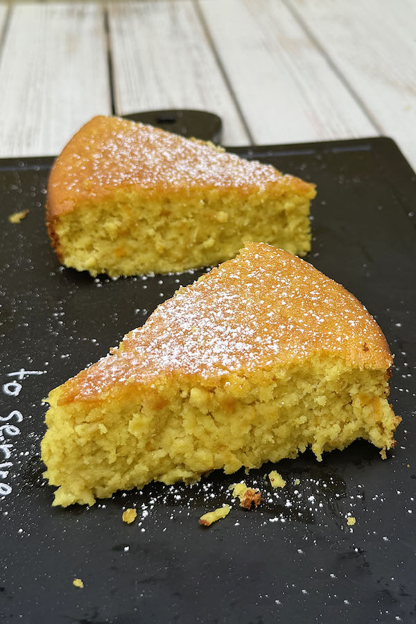 Two pieces of homemade blender orange cake sprinkled with powdered sugar.