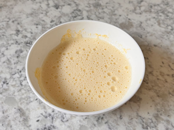 Яичные желтки, взбитые с сахарной пудрой в миске.