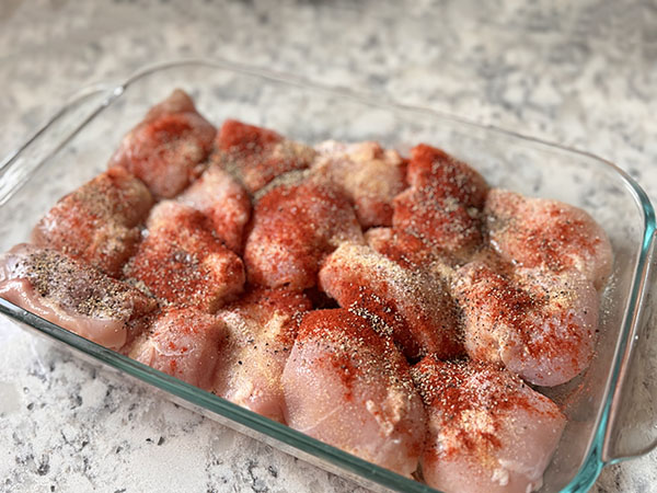 Skinless boneless chicken thighs with aromatic spices on top.