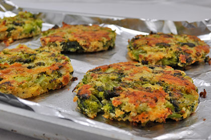 Baked Broccoli Patties served on a plate with a piece of parchment paper between patties. Fully baked broccoli patties removed from the oven.