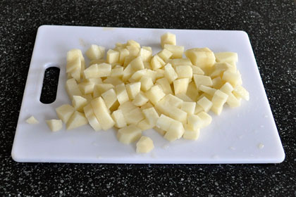 Russian Meatball Soup photo instruction 1 Potatoes cut into bite-sized cubes on a cutting board.