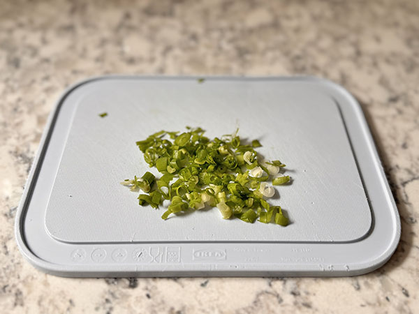 Finely chopped green onion on a cutting board.