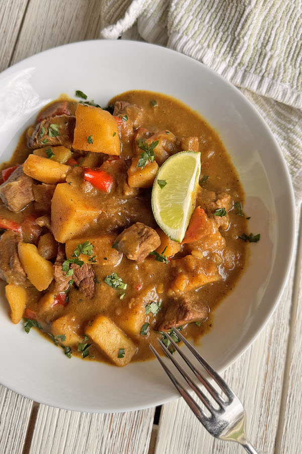 Spicy Beef Curry with Indian and Japanese Fusion in a bowl, garnished with chopped parsley and a lime wedge.