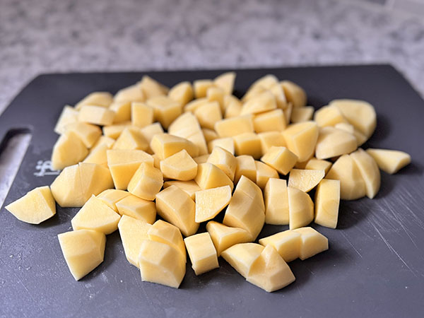 Potatoes cut into cubes on a cutting board.