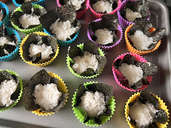 Nori cups with rice at the bottom, inserted in muffin cups so they hold shape.