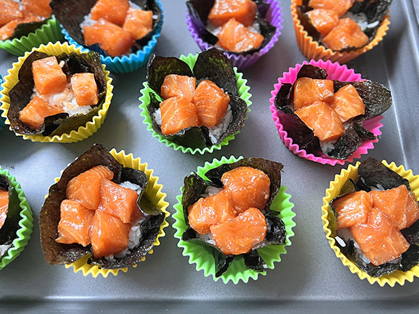 Nori cups with rice and pieces of marinated salmon, ready for baking.